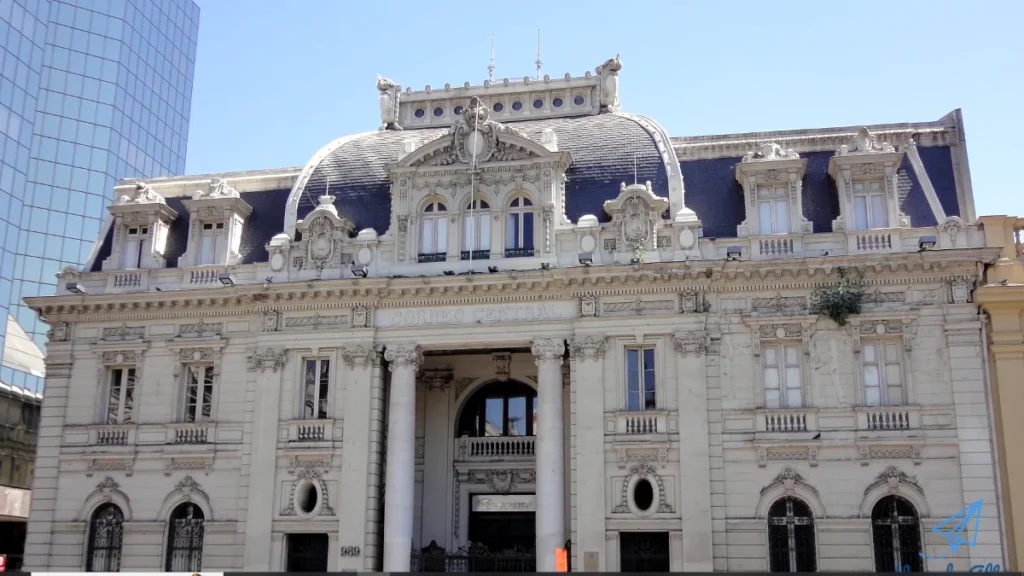 Edifício histórico com detalhes arquitetônicos intrincados, com arranha-céus modernos ao fundo.