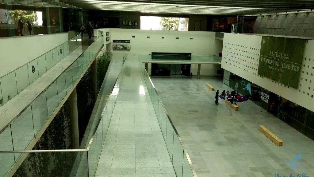 Vista interna de um edifício moderno com passarelas de vidro e área de estar.