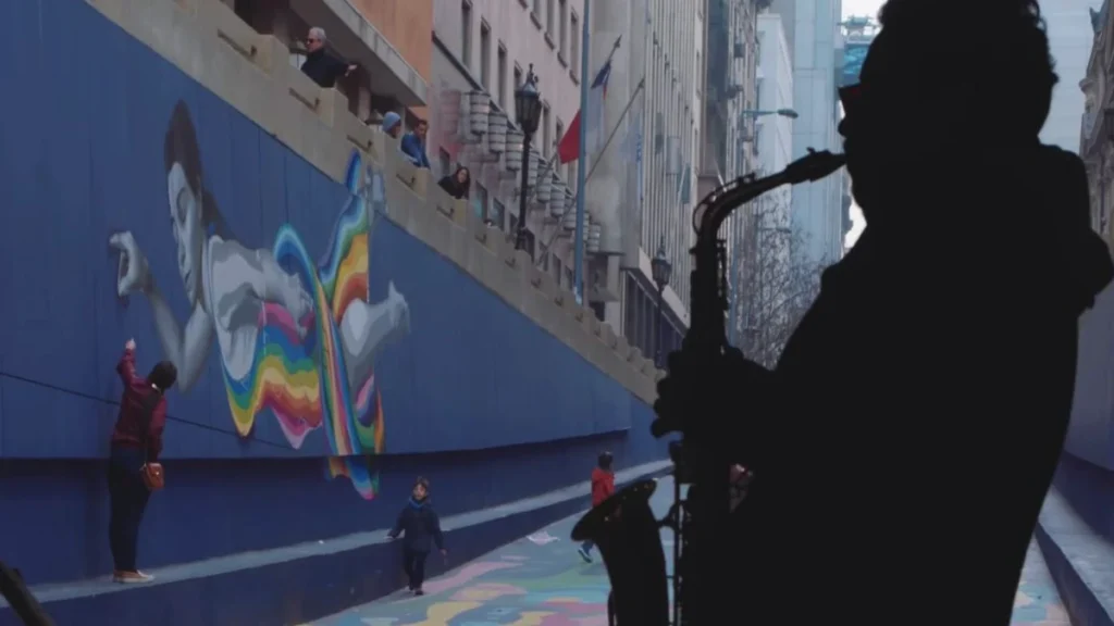 Arte de rua em Santiago com mural colorido e saxofonista tocando ao fundo.