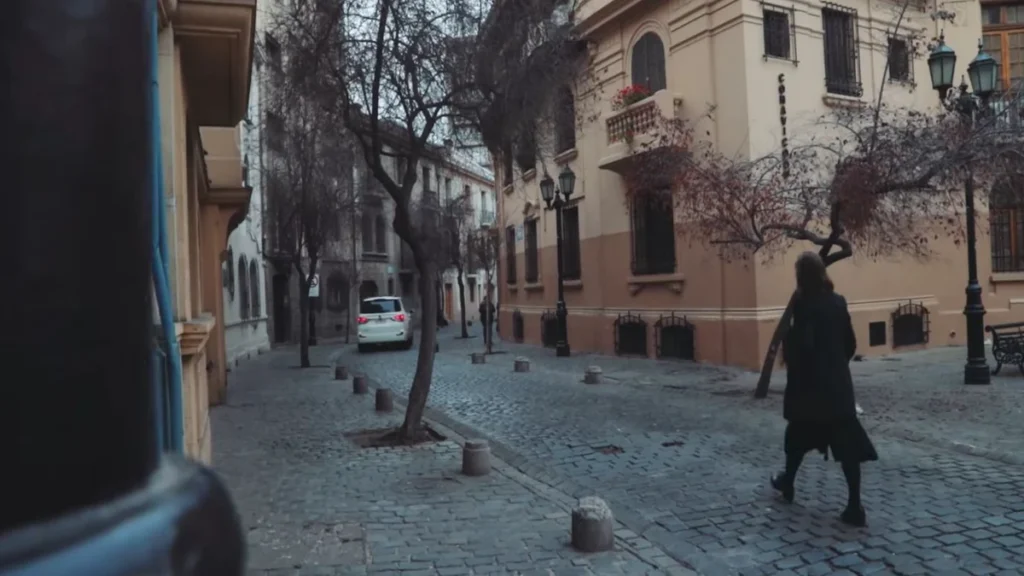 Rua de paralelepípedos com árvores secas e arquitetura histórica em Santiago.