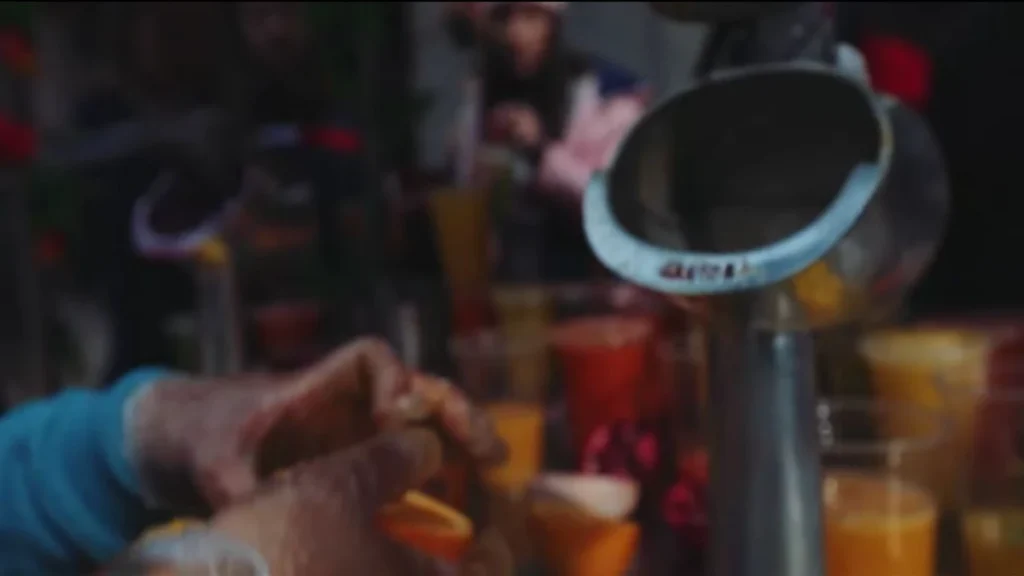 Pessoa espremendo suco de laranja em um mercado de rua em Santiago.