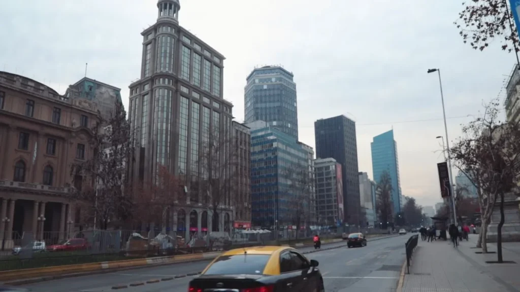 Vista de edifícios modernos em Santiago com um táxi amarelo na rua.