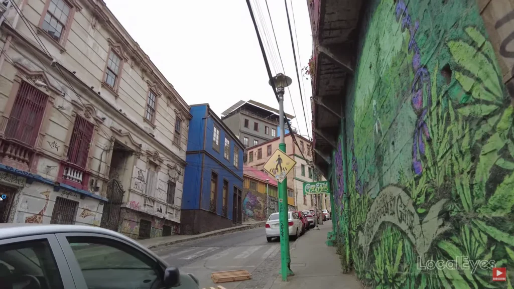 Rua íngreme de Valparaíso com casas coloridas e arte urbana nas paredes
