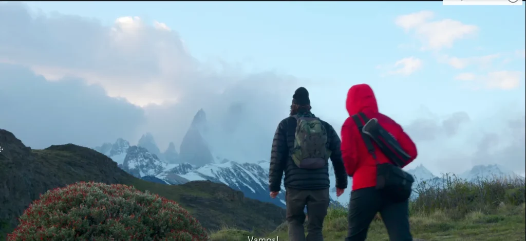Hikers em trilha com montanhas cobertas de neve ao fundo