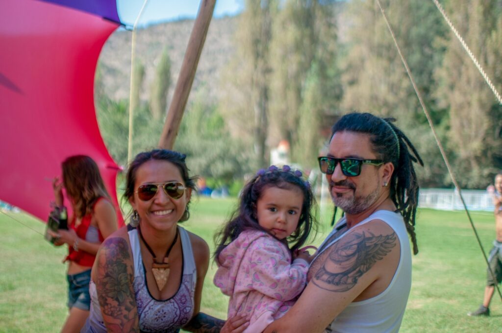 homem carregando menina pequena ao lado de mulher sorridente sob um dossel