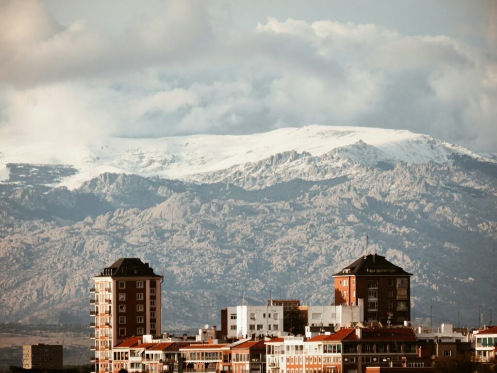 edifícios de concreto marrom e branco perto de uma montanha coberta de neve durante o dia
