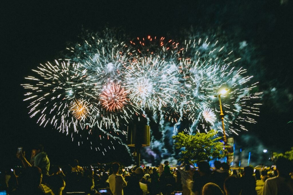 uma multidão de pessoas a assistir a uma exibição de fogos de artifício