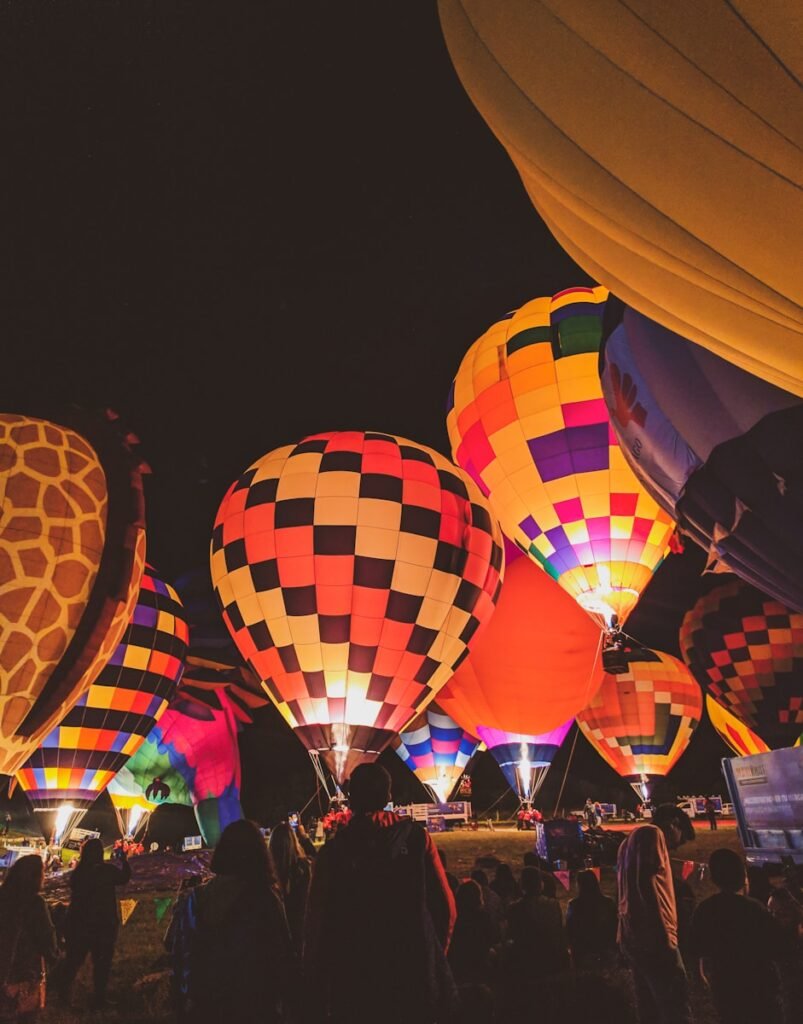 group of people on grass field with hot air balloons