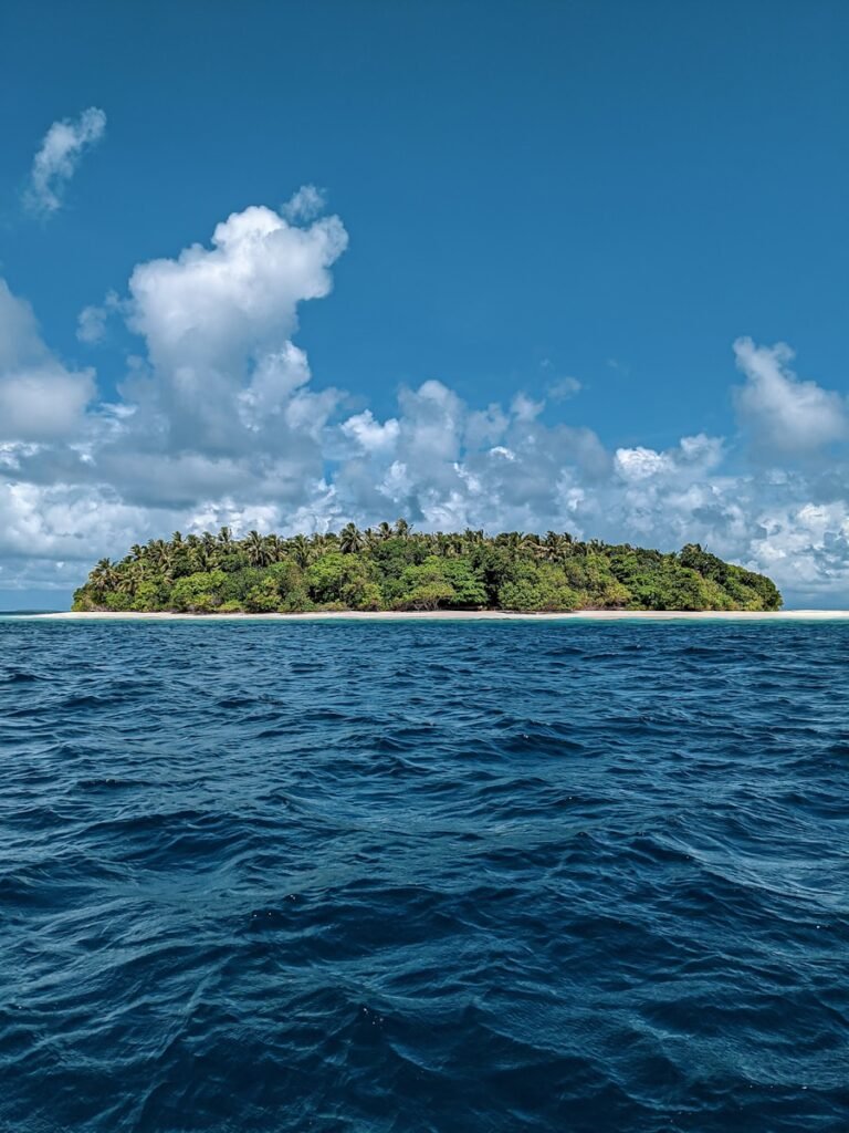 ilha verde rodeada de mar azul sob céu nublado azul e branco durante o dia