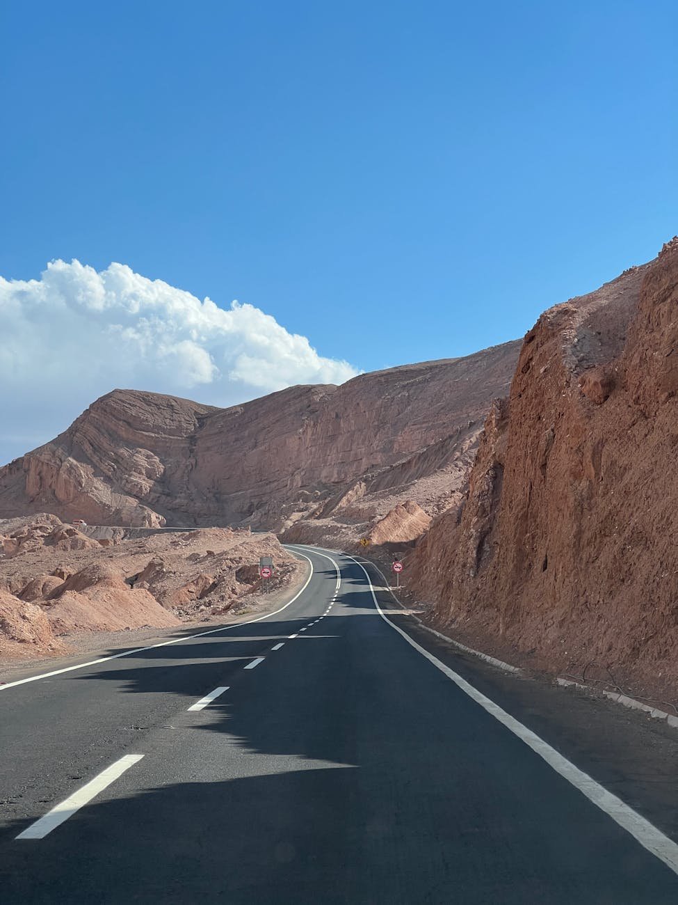 estrada de asfalto cinza ao lado da montanha rochosa marrom