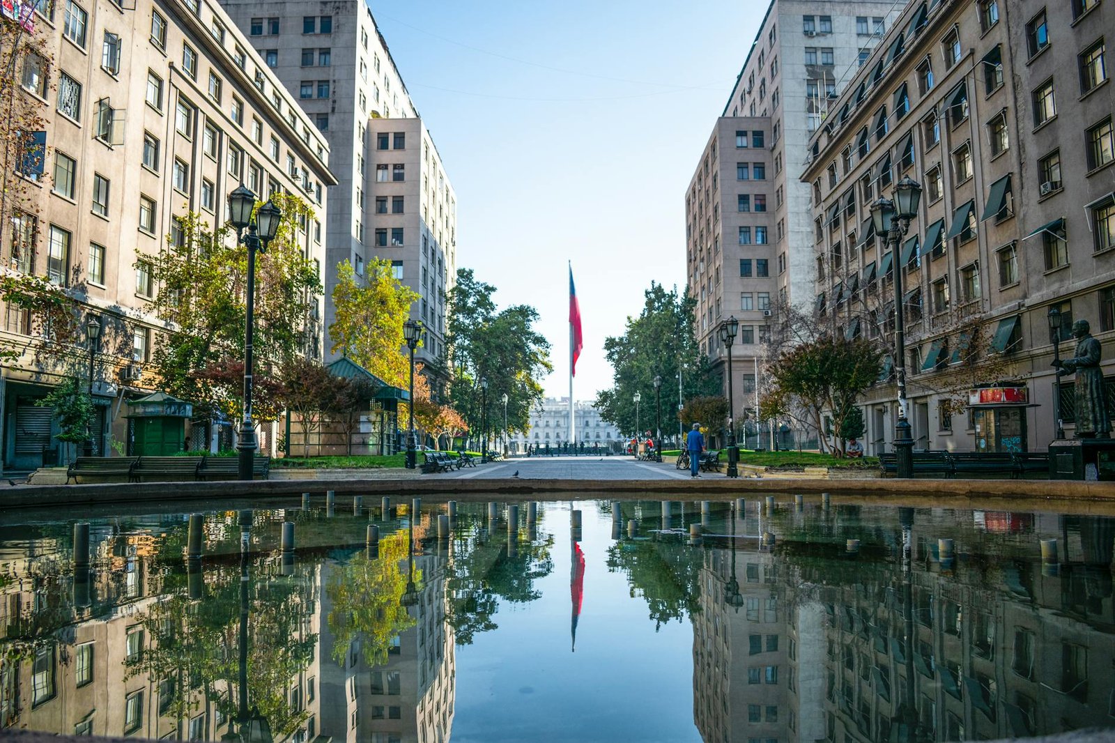 um reflexo dos edifícios e do mastro da bandeira na água da fonte