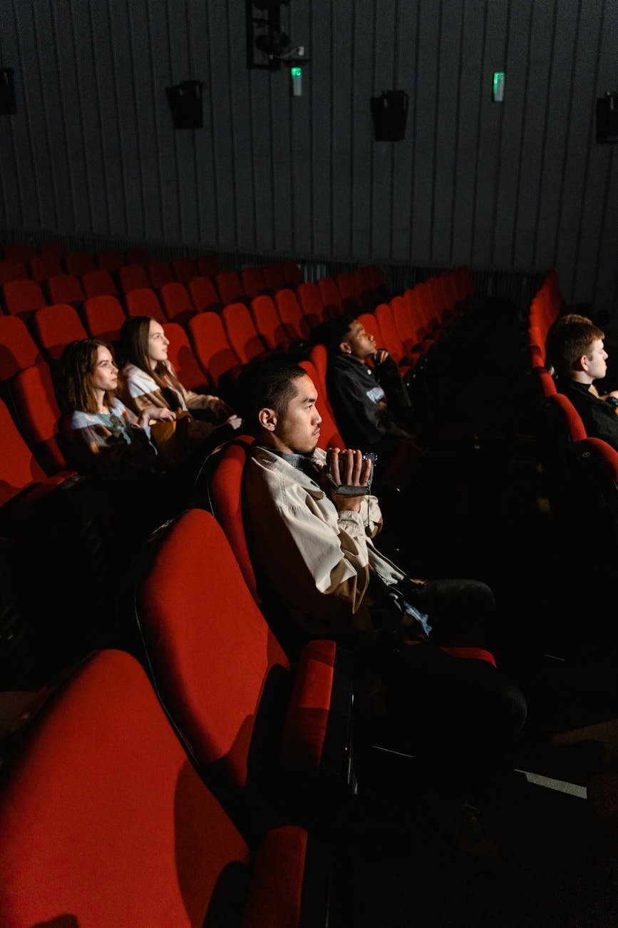 pessoas sentadas em uma cadeira enquanto assistem a um filme seriamente