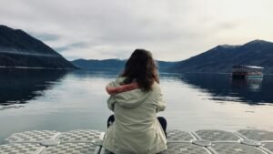 woman wearing gray jacket in front of body of water