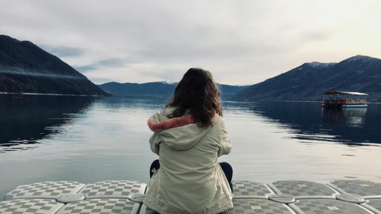 woman wearing gray jacket in front of body of water