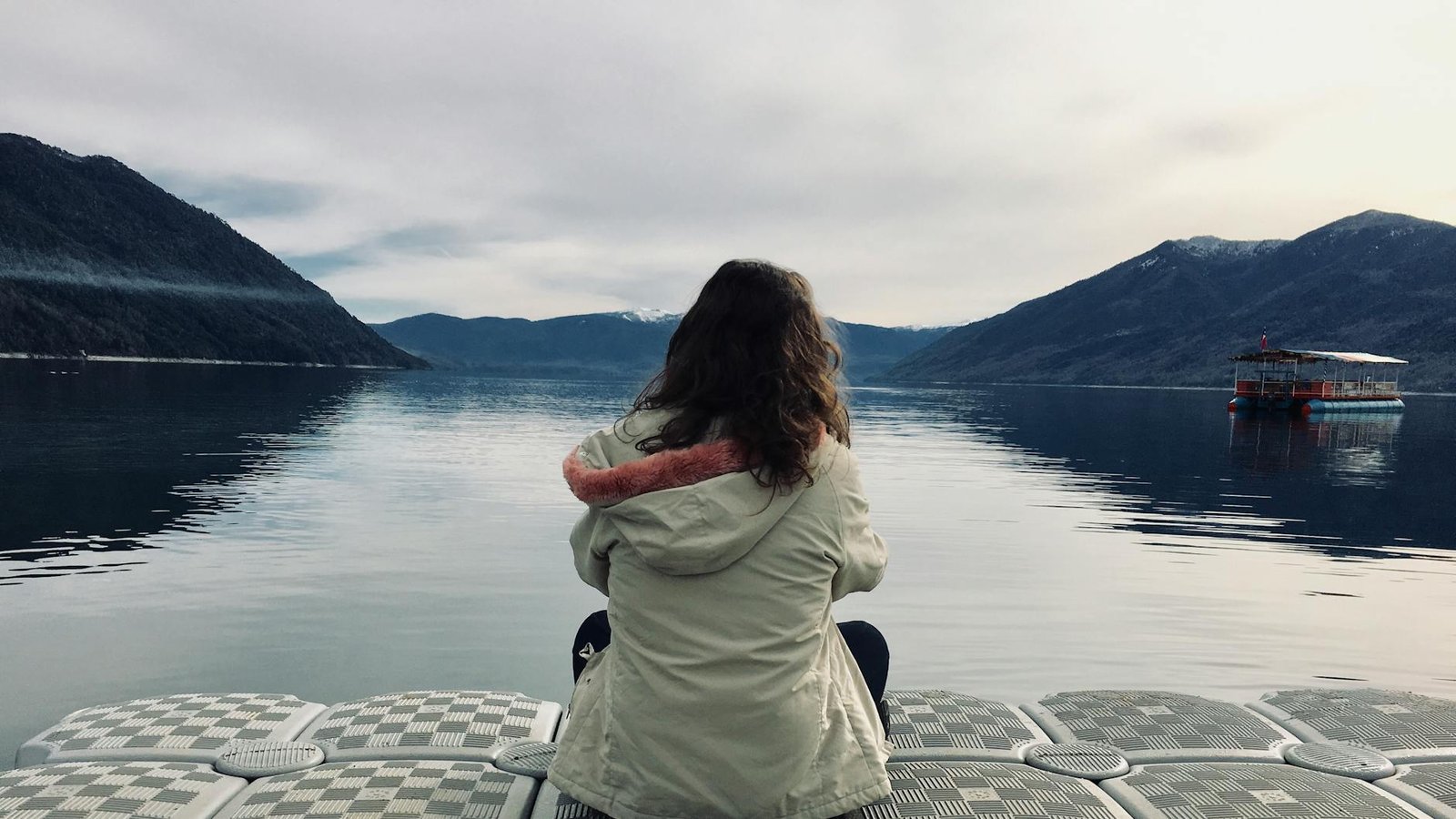 woman wearing gray jacket in front of body of water