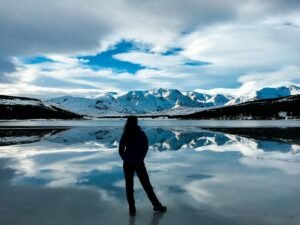 silhouette photo of woman facing snow capped mountain