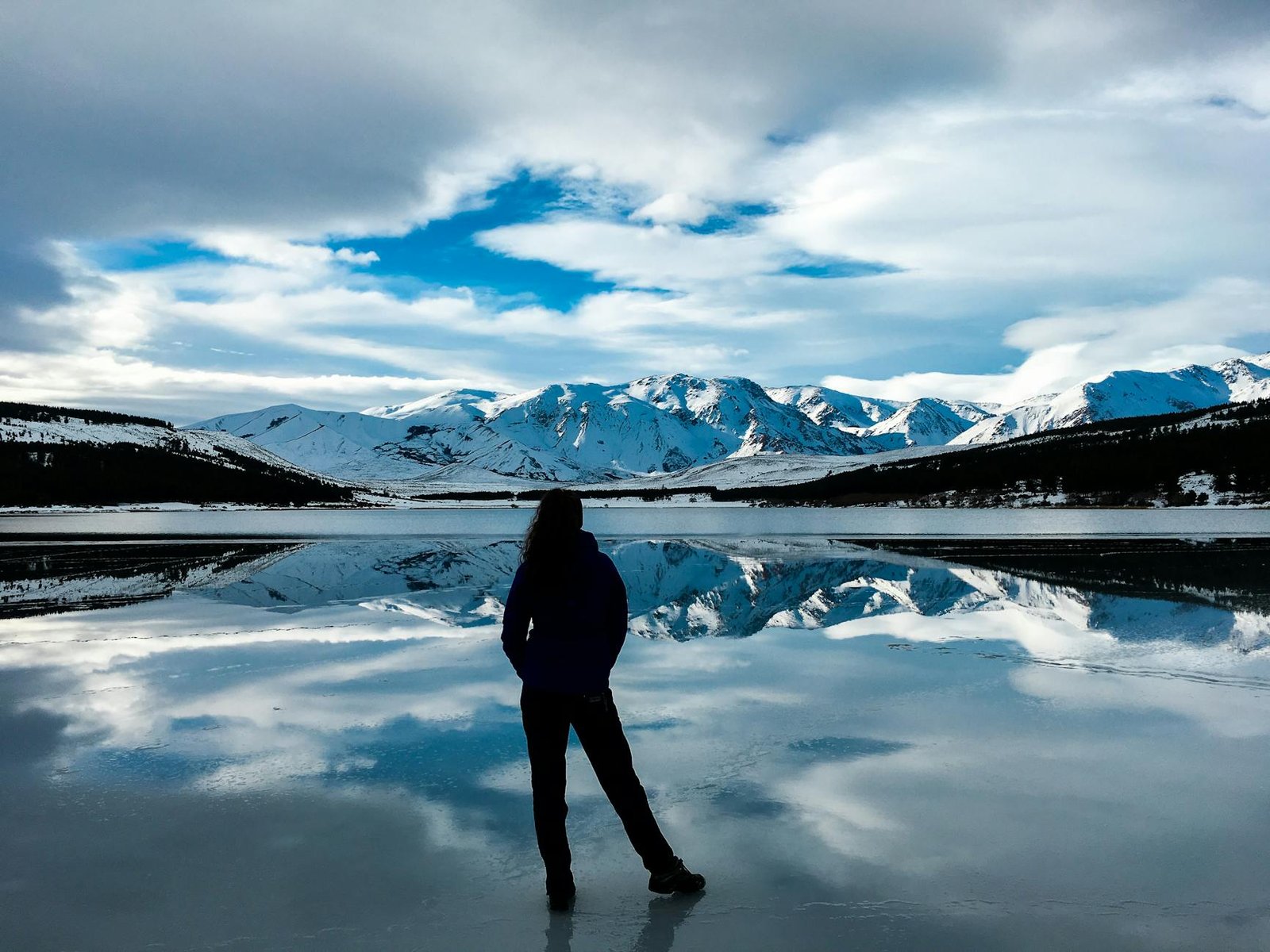 silhouette photo of woman facing snow capped mountain