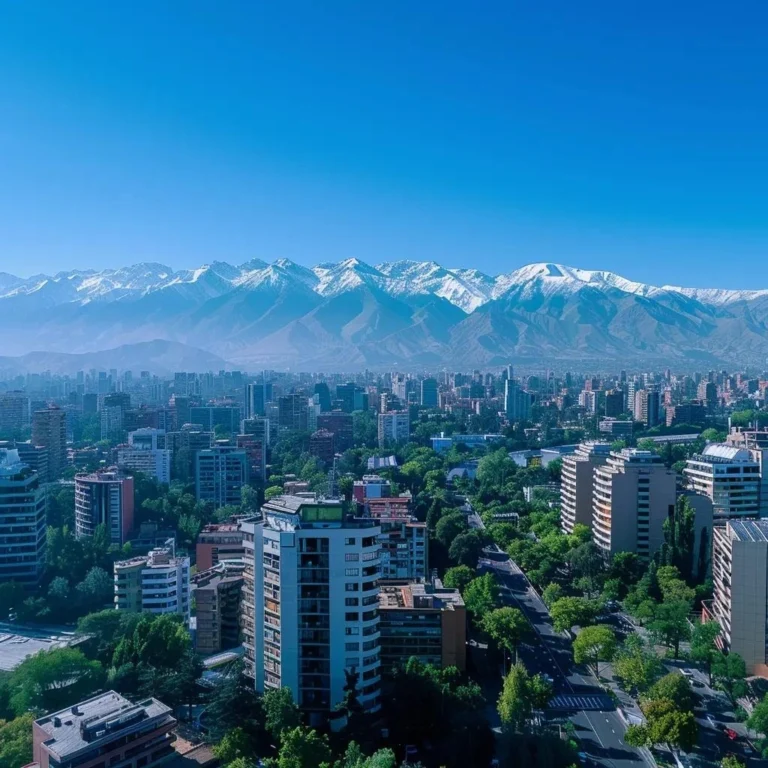 uma vista impressionante de santiago, chile, em um dia ensolarado, com o céu azul emoldurando as majestosas montanhas dos andes ao fundo, enquanto o primeiro plano exibe elementos urbanos como edifícios modernos e árvores verdejantes, capturando a essência climática da cidade.