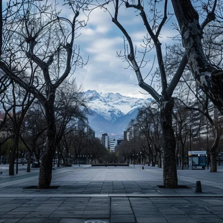 uma cena urbana de santiago em junho, com um céu nublado e os andes cobertos de neve ao fundo, apresentando uma praça tranquila com árvores sem folhas, refletindo a calma de um dia frio de inverno.