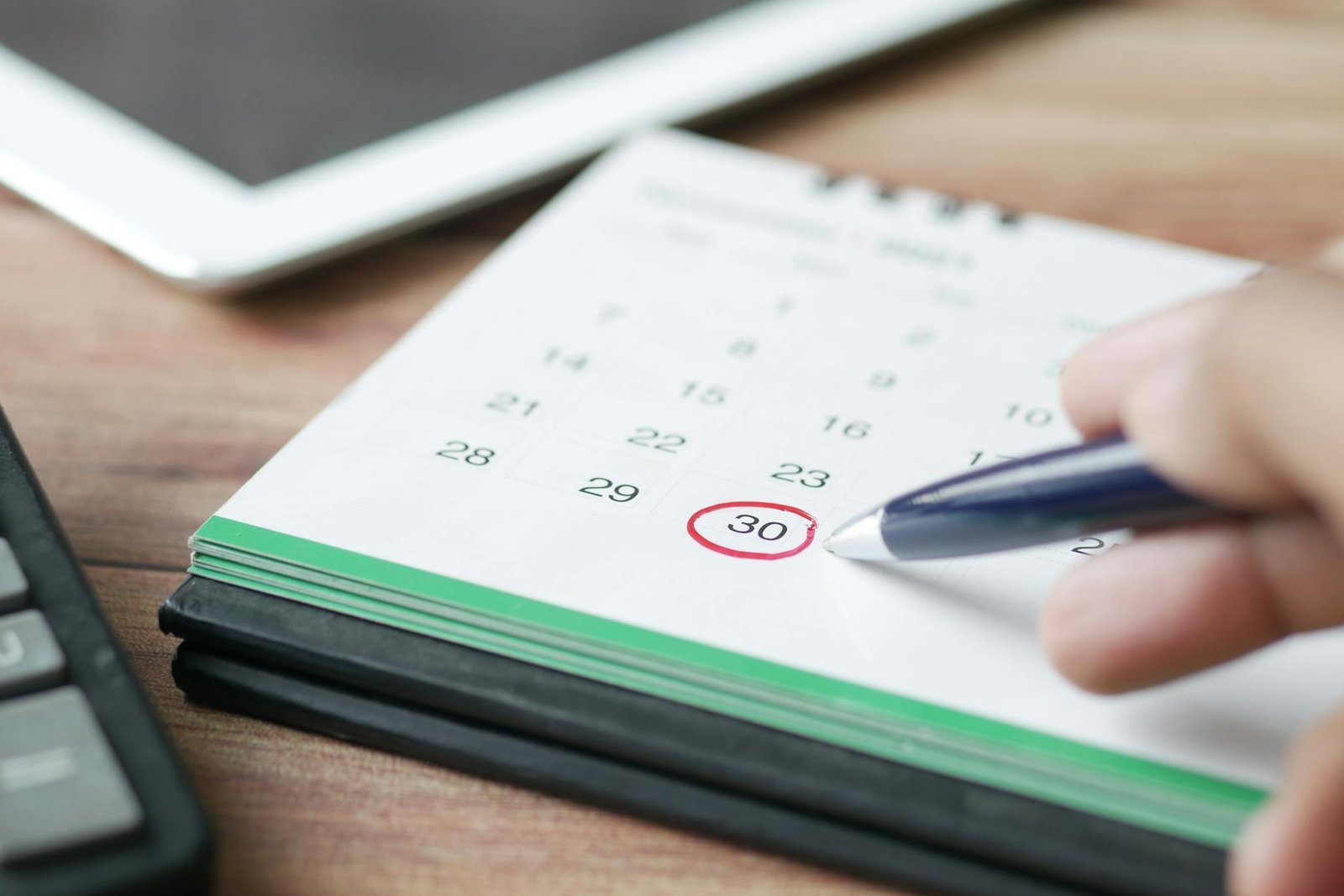 uma pessoa segurando uma caneta preta apontando para um calendário