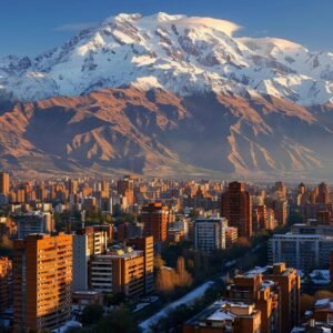 uma vista impressionante das montanhas dos andes no chile em dezembro, com picos cobertos de neve no topo e, na base, uma cidade ensolarada onde moradores estão vestidos para o verão, enquanto alguns esquiam nas encostas nevadas, evidenciando a diversidade climática do país.