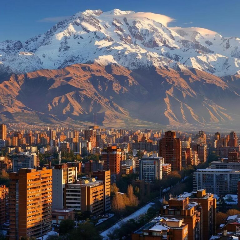 uma vista impressionante das montanhas dos andes no chile em dezembro, com picos cobertos de neve no topo e, na base, uma cidade ensolarada onde moradores estão vestidos para o verão, enquanto alguns esquiam nas encostas nevadas, evidenciando a diversidade climática do país.