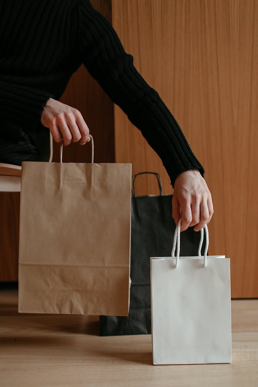 pessoa segurando sacolas de papel marrom e branco