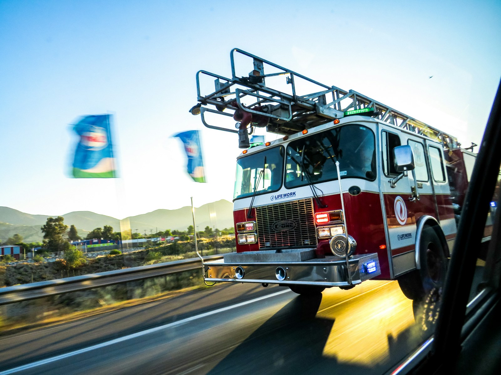 Caminhão de bombeiros dirigindo em uma rodovia ao pôr do sol