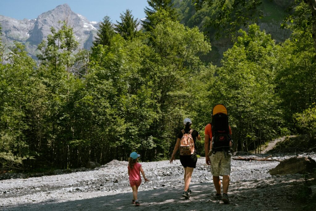 Família fazendo trilha em meio à natureza e montanhas, seguindo dicas de viagem em família para o ecoturismo.