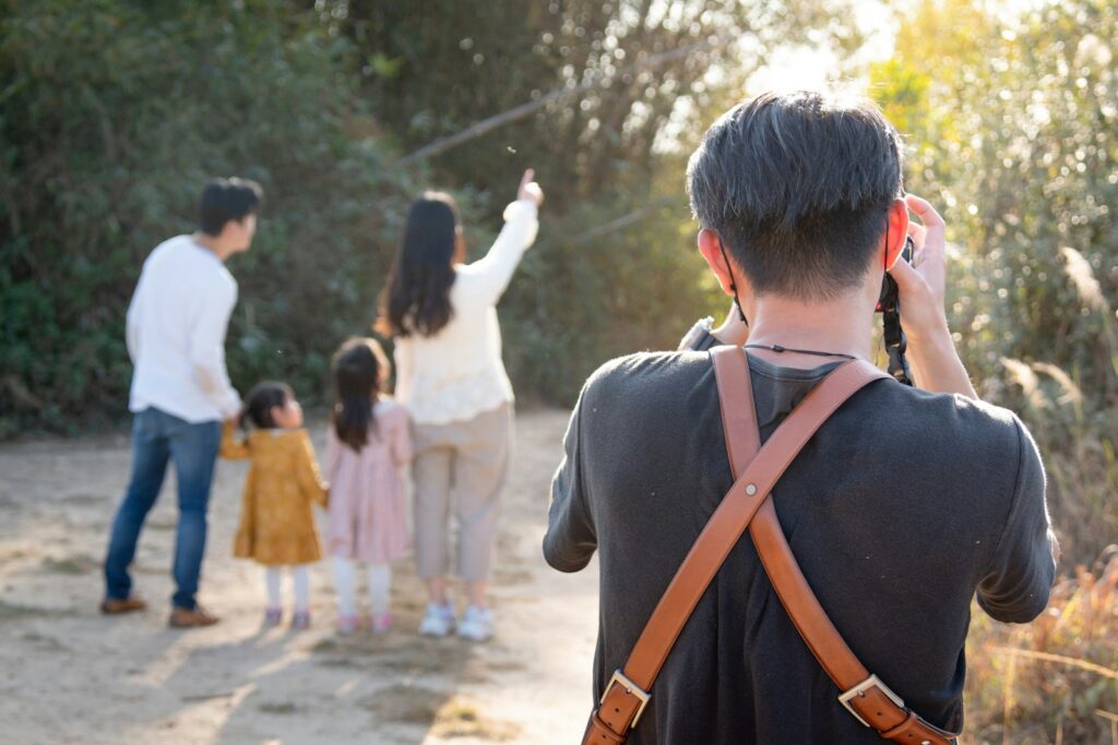 Pai fotografando a família caminhando na natureza com segurança, seguindo as melhores dicas de viagem em família.