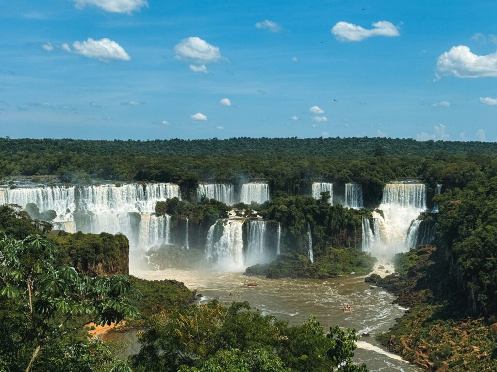 Vista panorâmica de um grande complexo de cataratas com várias quedas d'água potentes cercadas por floresta tropical densa.