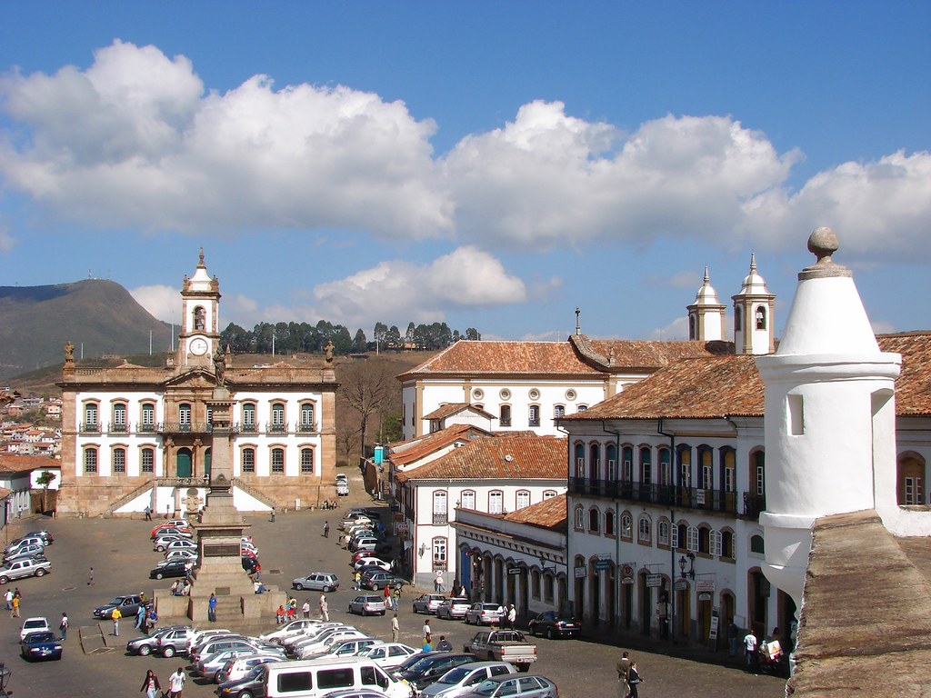 Vista panorâmica da Praça Tiradentes e do Museu da Inconfidência em Ouro Preto, com arquitetura colonial e céu azul.