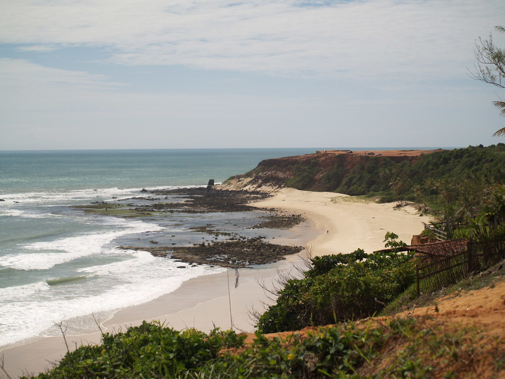 Vista da Praia do Madeiro ou similar em Pipa, RN, com falésias avermelhadas e mar verde.