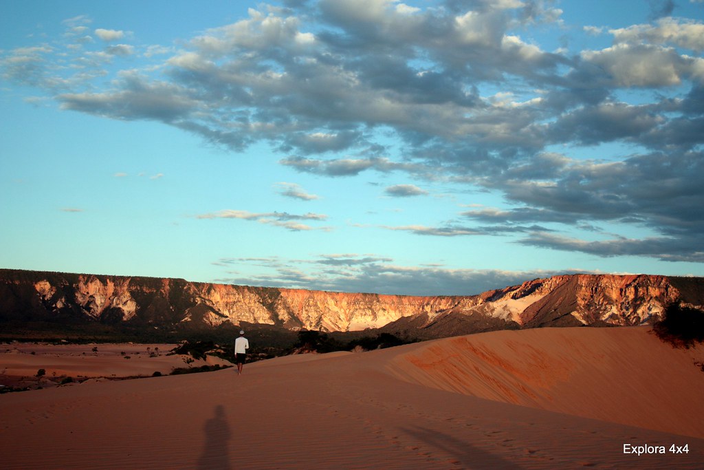 Turista caminhando sobre as dunas douradas do Jalapão com a Serra ao fundo, destaque do turismo ecológico do Brasil no Tocantins.