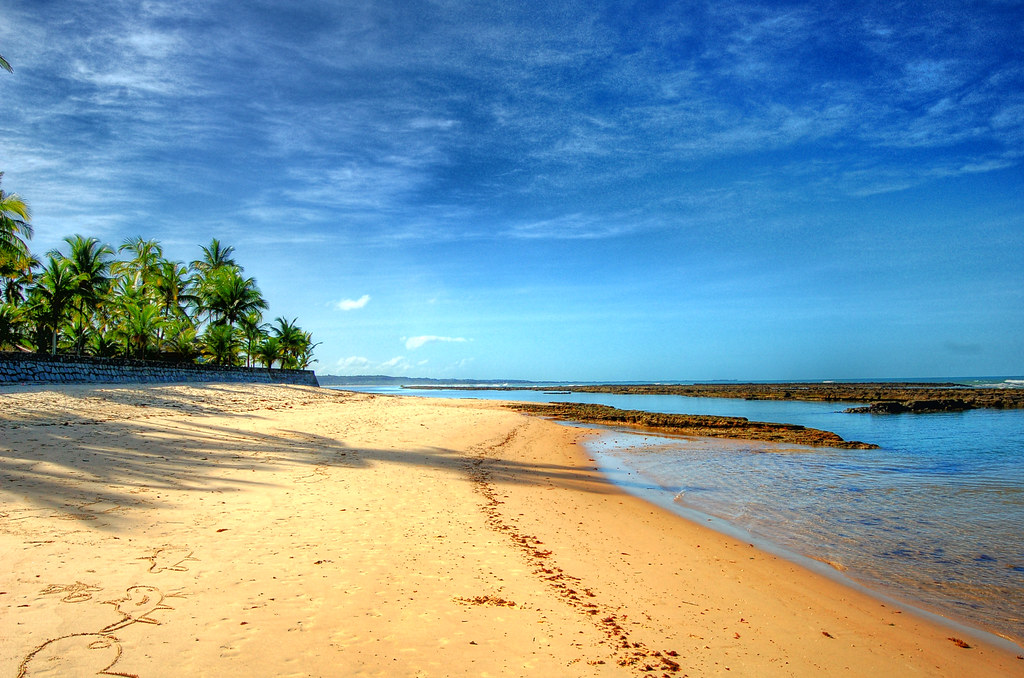 Praia paradisíaca em Arraial d'Ajuda com maré baixa, arrecifes e coqueiros, ideal para banho de crianças pequenas.
