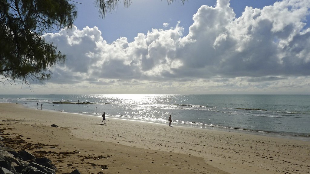 Praia com maré baixa revelando recifes e águas brilhantes sob o sol, típica paisagem dos passeios para Recife de Fora.