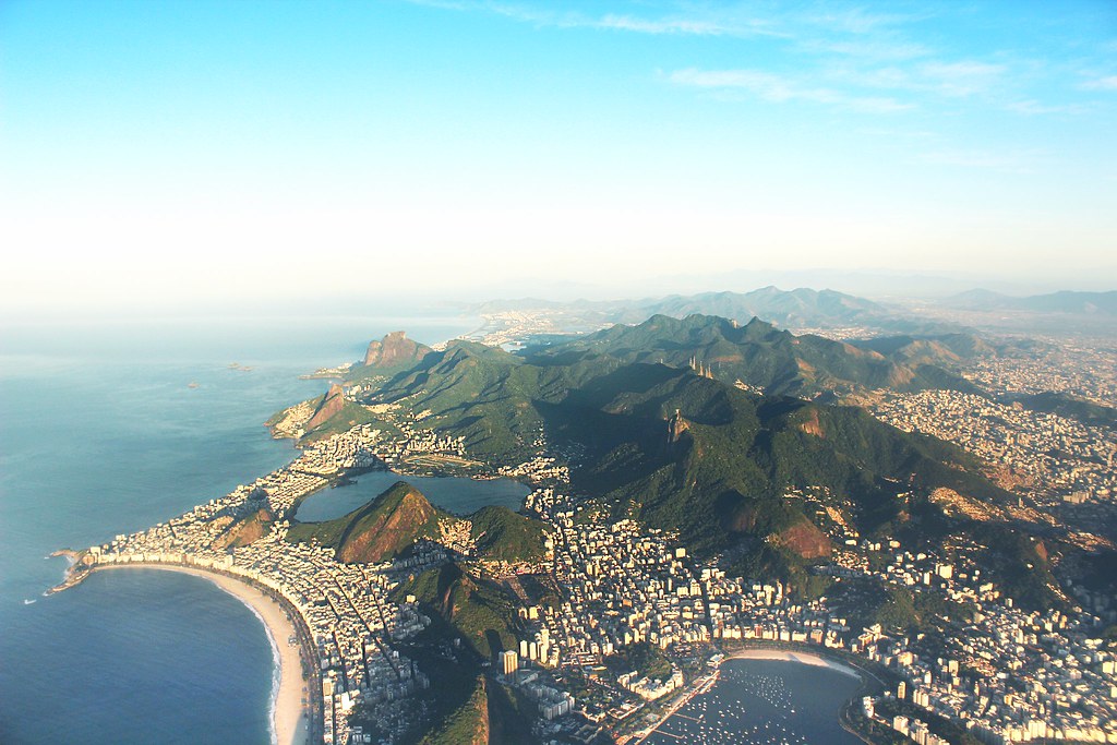 Vista aérea panorâmica do Rio de Janeiro mostrando o Cristo Redentor, a Lagoa Rodrigo de Freitas e as praias de Ipanema e Copacabana.