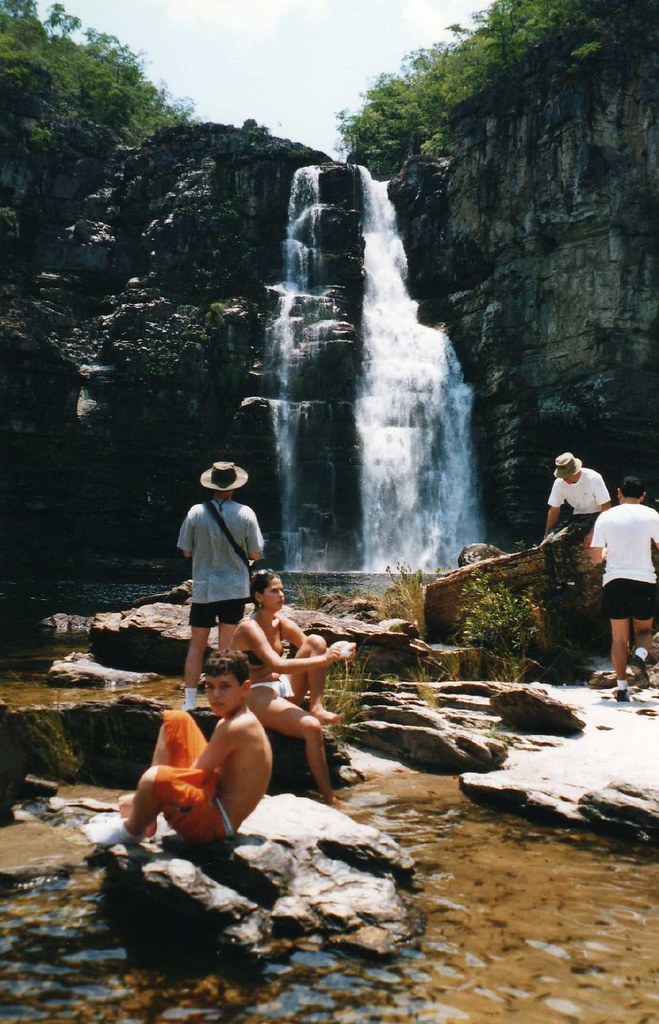 família descansando nas pedras em frente a uma grande cachoeira na Chapada dos Veadeiros