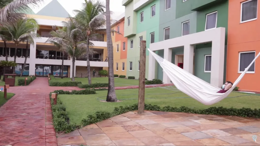 Hóspede relaxando em uma rede branca no jardim do resort.