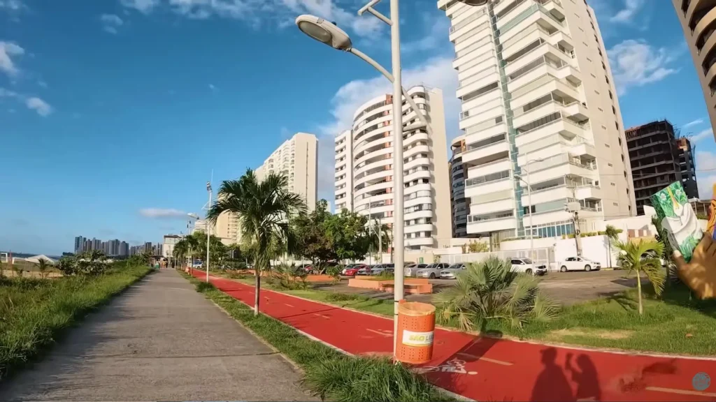 Ciclovia vermelha e calçadão arborizado com coqueiros e prédios modernos ao fundo em São Luís.