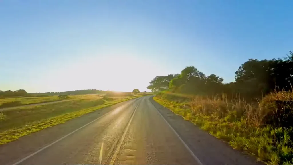 Estrada asfaltada cortando a paisagem rural durante o pôr do sol.