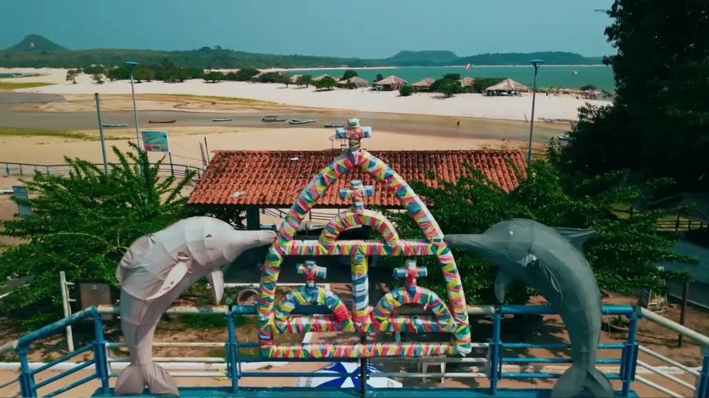 Mirante com estátuas de botos e arco colorido em frente à praia, passeios, natureza, Brasil.