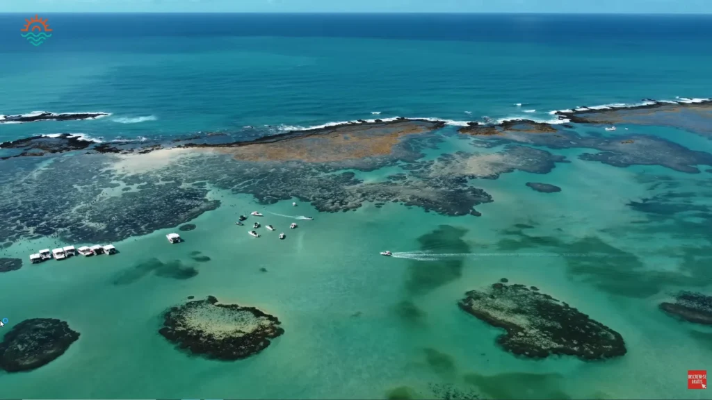 Vista aérea panorâmica da costa de Maragogi mostrando os recifes e piscinas naturais.