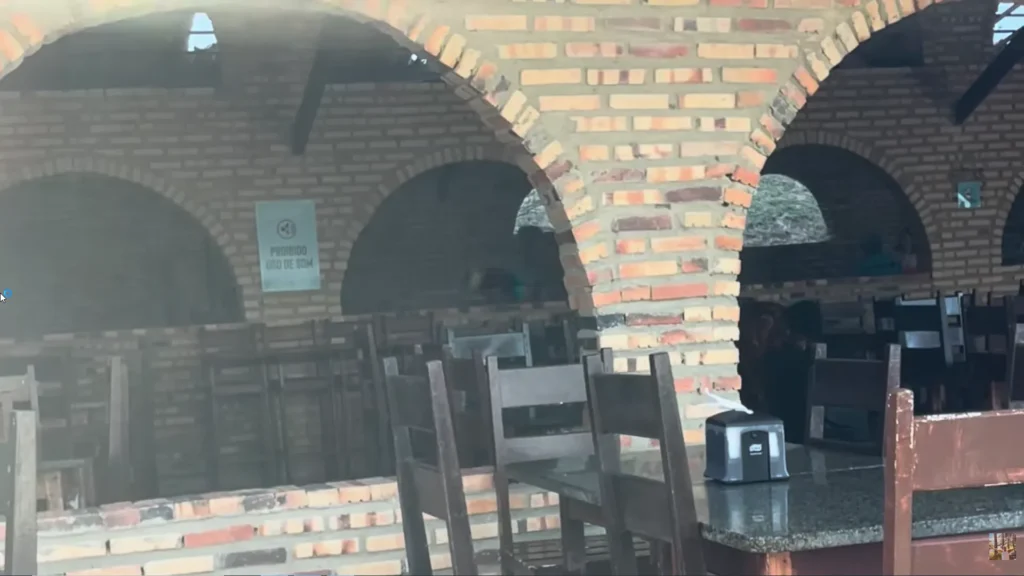 Salão de refeições com mesas de madeira e grandes arcos de tijolos aparentes no Coliseum Beach Resort, uma estrutura única entre os melhores resorts do Nordeste.