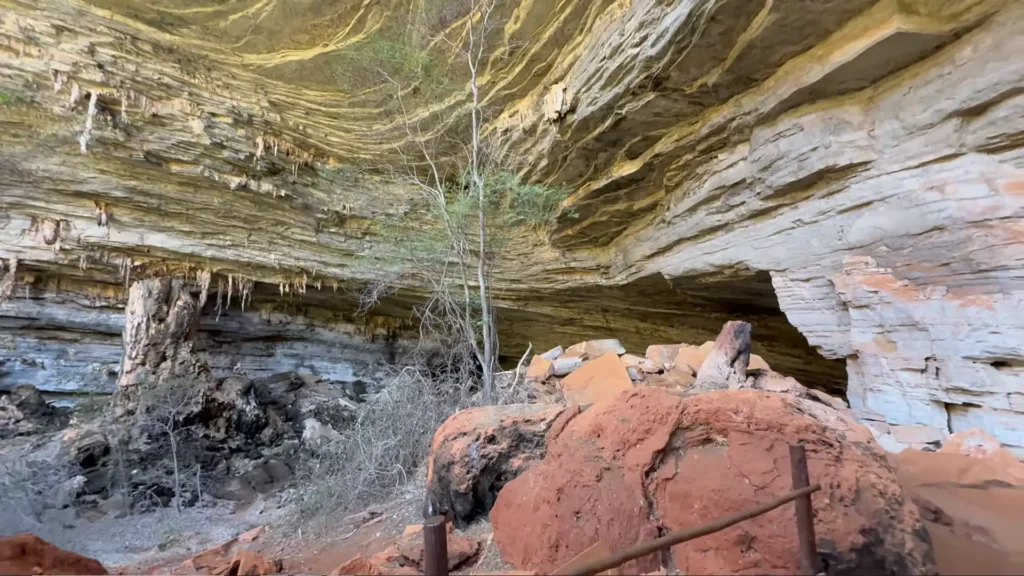 interior amplo de uma gruta com teto rochoso alto e formações geológicas.