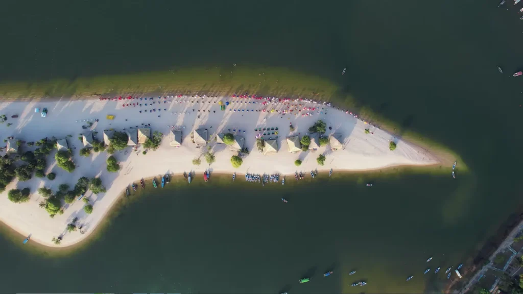 Vista aérea vertical da praia de areia branca com guarda-sóis coloridos e turistas em Alter do Chão, um destaque entre as cidades pitorescas brasil.