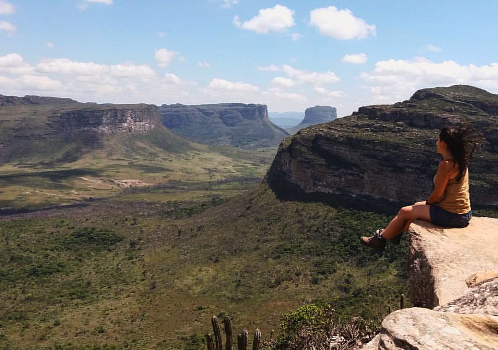 Turista sentada em um penhasco no Morro do Pai Inácio observando os vales da Chapada Diamantina, Bahia.