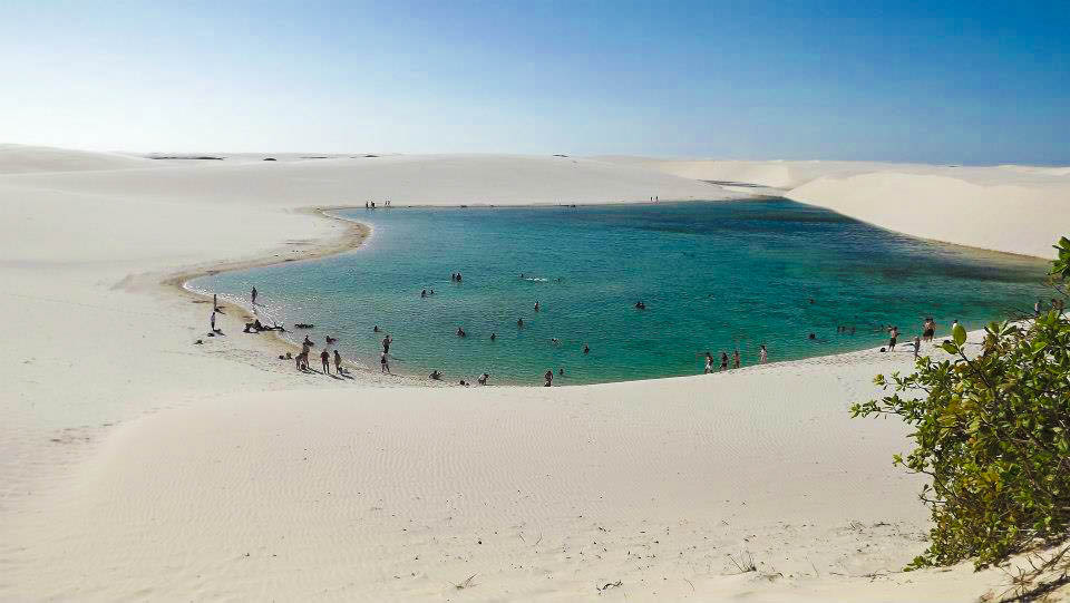 Lagoa de águas cristalinas cercada por dunas de areia branca nos Lençóis Maranhenses em passeios natureza brasil.