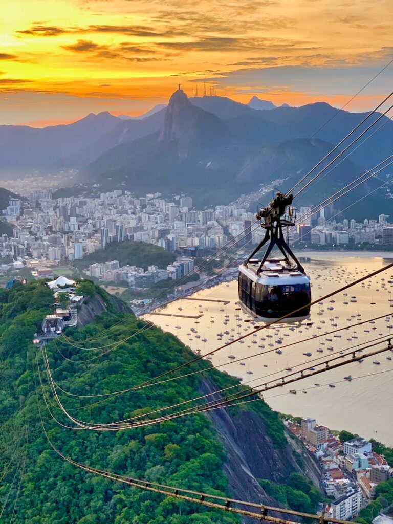 Bondinho do Pão de Açúcar ao pôr do sol com o Cristo Redentor ao fundo no Rio de Janeiro.