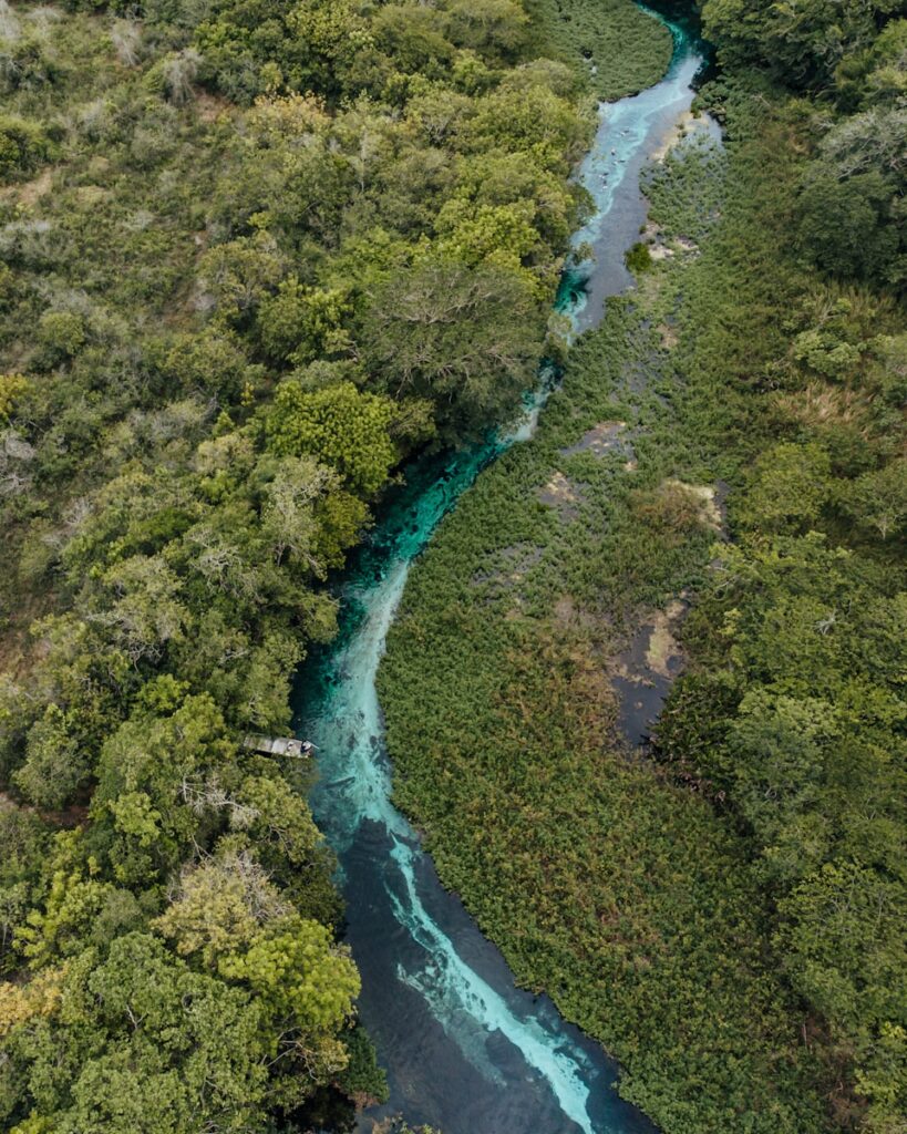 vista aérea de rio com água transparente serpenteando a mata, um dos melhores lugares para passear com crianças e praticar flutuação em Bonito.